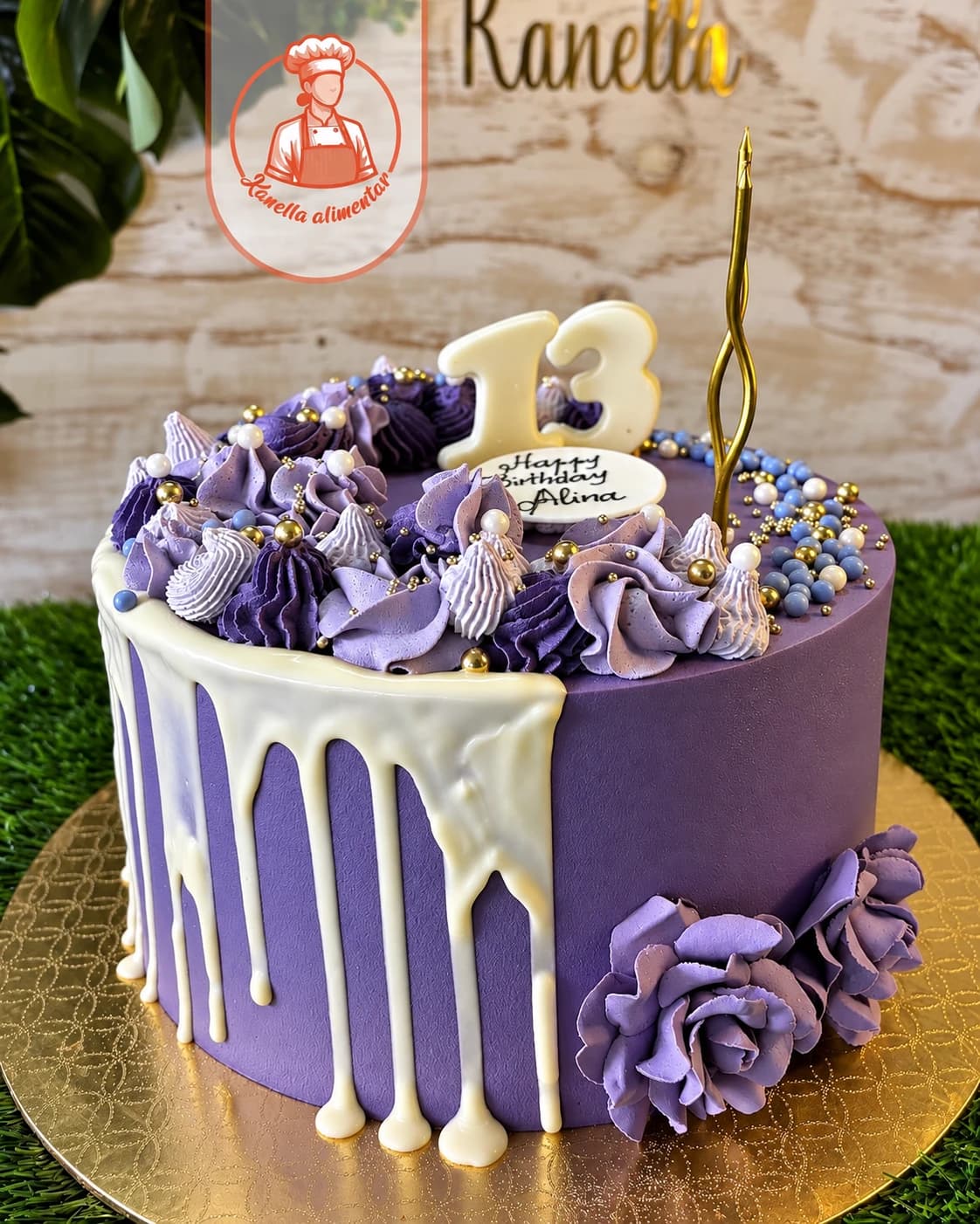 Bolo de aniversário roxo com chocolate branco a escorrer, rosas de creme lilás, pérolas e detalhes dourados