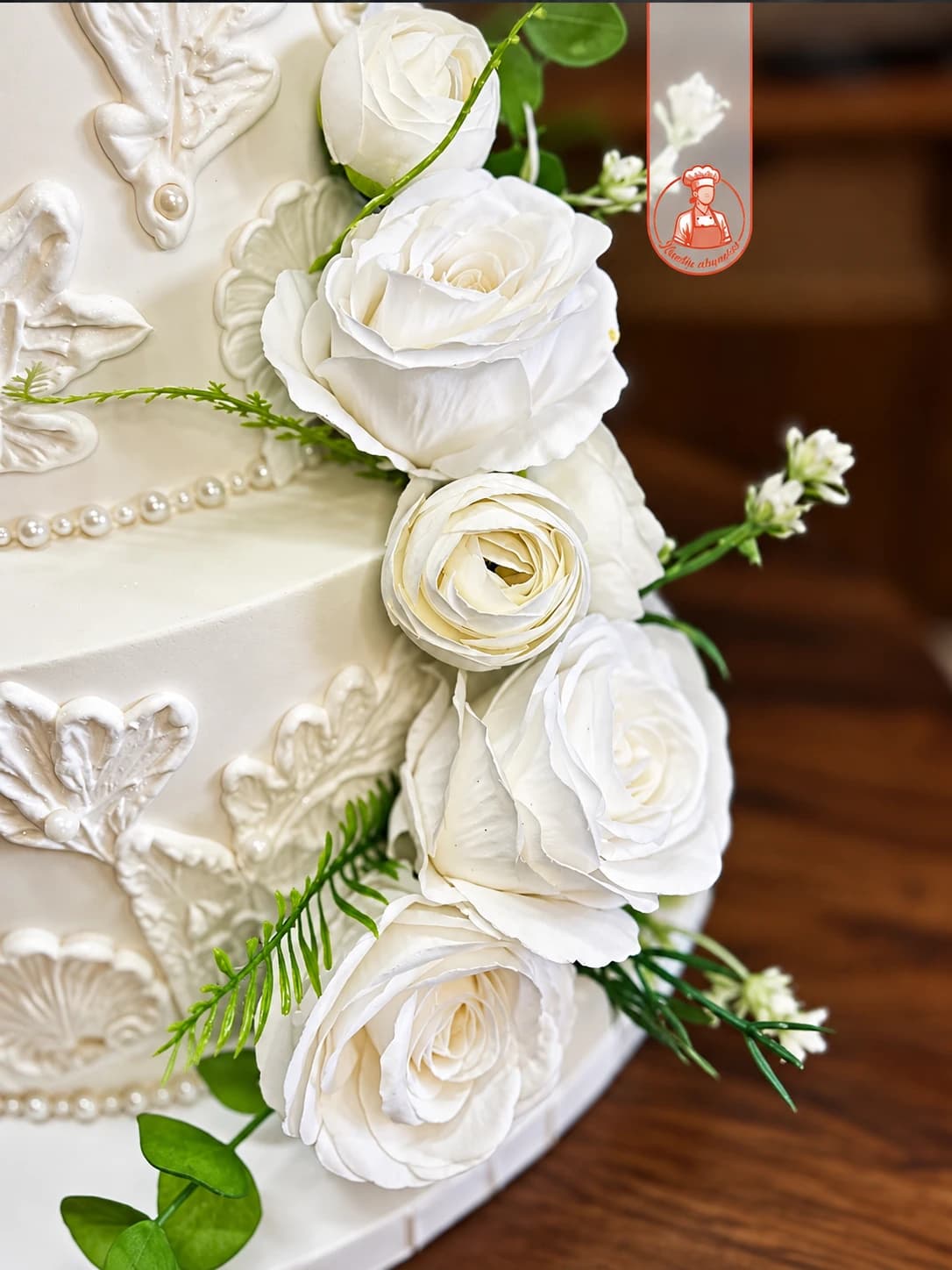 Pormenor de rosas brancas e relevos em pasta de açúcar num bolo de casamento